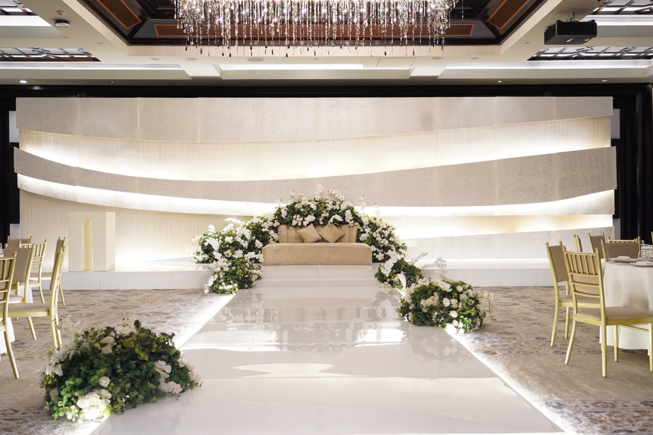 Luxury hotel ballroom set for a wedding with a white floral aisle and gold chiavari chairs