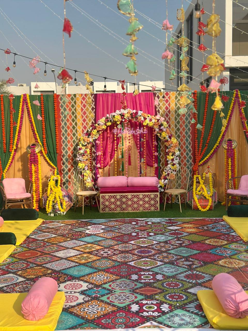 Colourful outdoor Mehndi setup with marigold garlands and a bright patterned floor