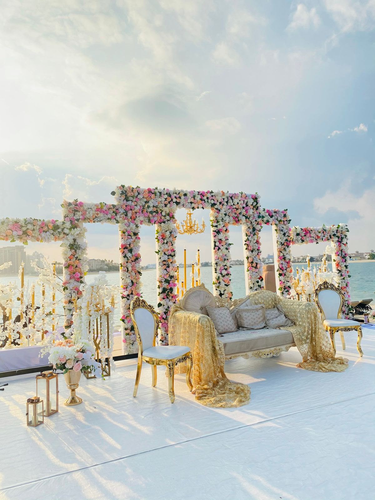 Beachfront wedding stage with a floral mandap and gold sofa by the sea in the UAE