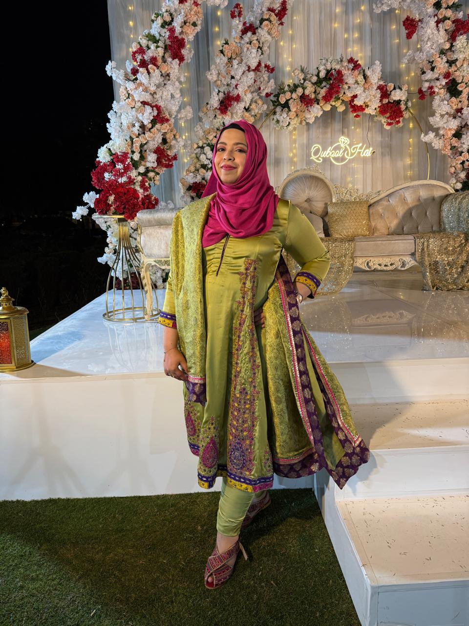 Maryam Sohail at a wedding she planned, standing by a floral reception backdrop