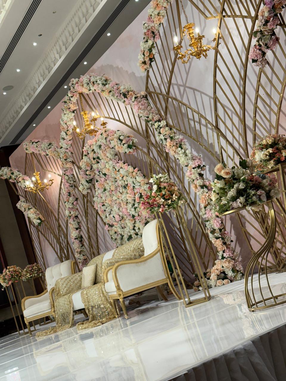 Gold and floral wedding stage backdrop with chandeliers in a hotel ballroom