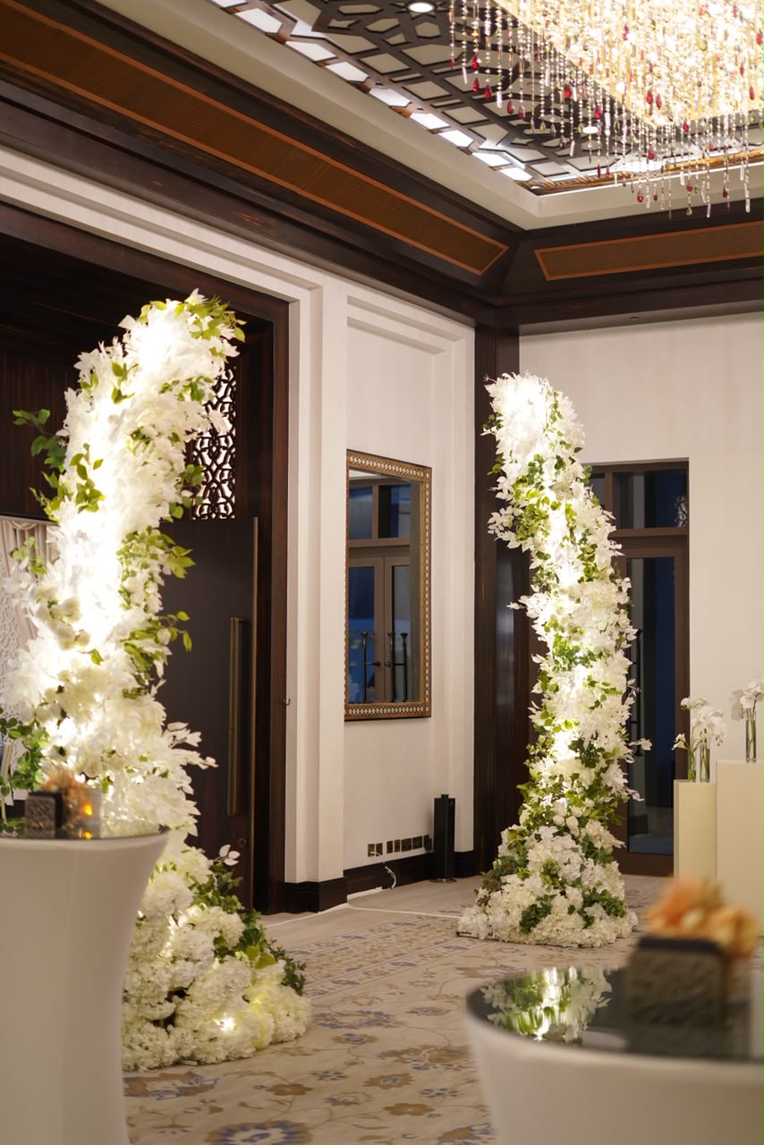 Hotel ballroom entrance framed by tall illuminated white floral pillars