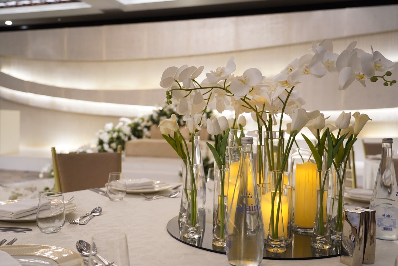 Wedding table centrepiece with white orchids and candles in an elegant ballroom